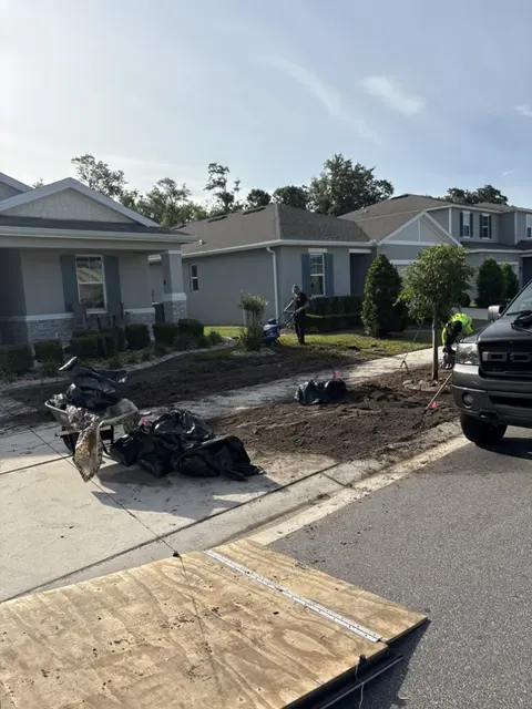 Old bed being torn out in front of a new home, debris bagged by the driveway