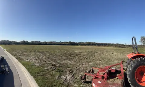 Tractor with a rotary cutter beside a large field that has just been cut down