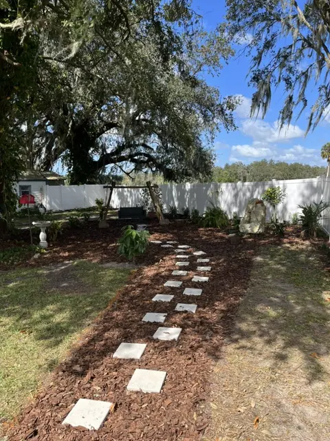 Fresh mulch bed with a stepping-stone path under a live oak