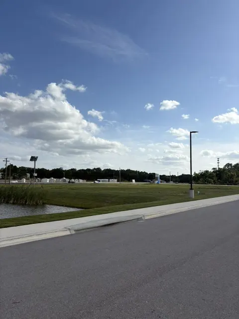 Mowed lawn running down to a pond along a new road