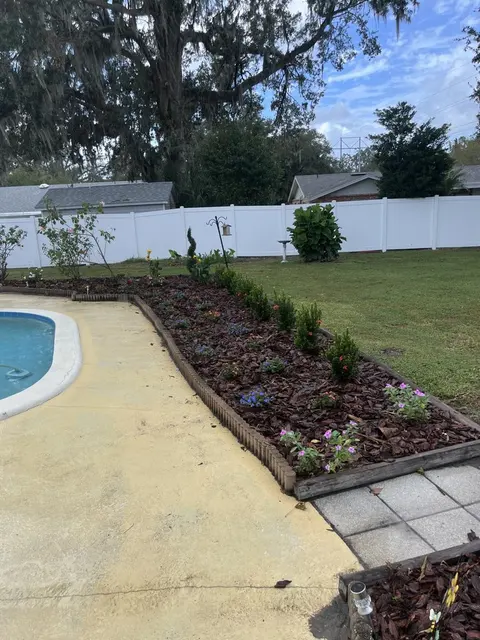 New mulched planting bed with an edged border beside a pool deck