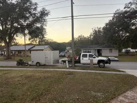 Work truck, enclosed trailer and mower at a residential lawn at sunset