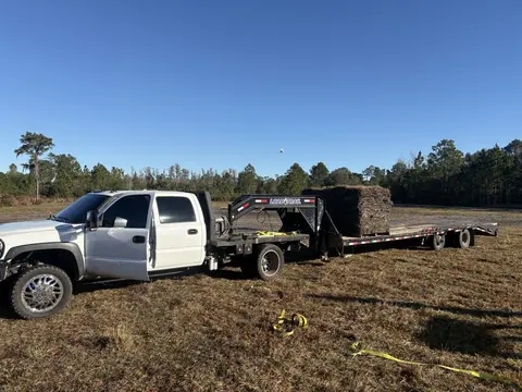 Pallets of sod on a gooseneck trailer behind the work truck in an open field